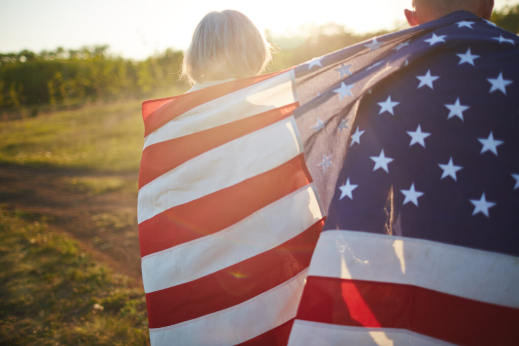 Senior couple wrapped into American flag taking walk